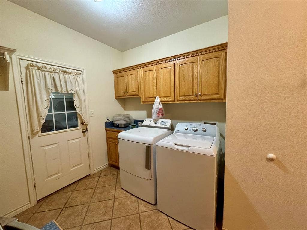 3700 NE County Road 0095, Corsicana, TX 75109 Utility area featuring wood-finish cabinetry, tile flooring, and exterior access door