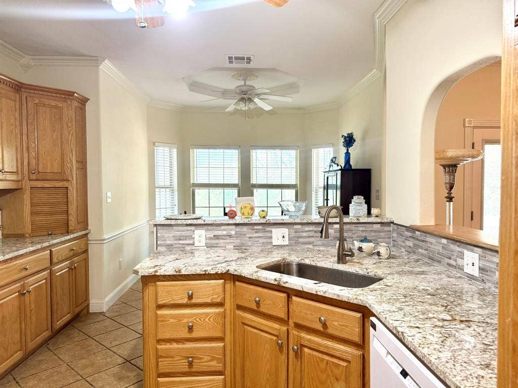 3700 NE County Road 0095, Corsicana, TX 75109 Kitchen featuring stone countertops, tile backsplash, natural finish wood cabinetry, under-mount sink with high-arch faucet, and crown molding
