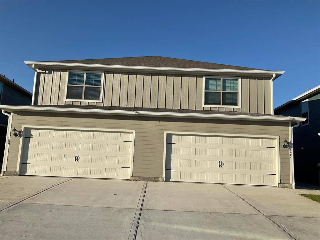 325 Stone Court, Princeton, TX 75407 Two-story exterior featuring vertical board-and-batten siding, horizontal lap siding, two individual garage bays, and a concrete driveway