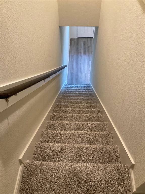 325 Stone Court, Princeton, TX 75407 Staircase featuring neutral carpeting, a dark wood-finish handrail, and white walls