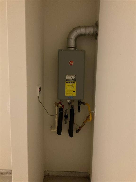 325 Stone Court, Princeton, TX 75407 Wall-mounted tankless water heater featuring metal venting, insulated piping, and integrated electronic control panel