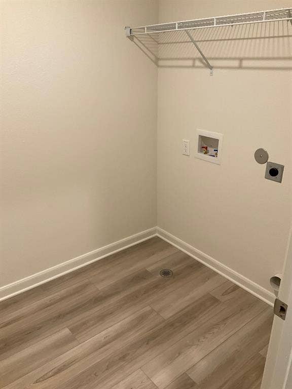 325 Stone Court, Princeton, TX 75407 Laundry area featuring wood-finish flooring, a white metal shelving unit, and dedicated utility hookups