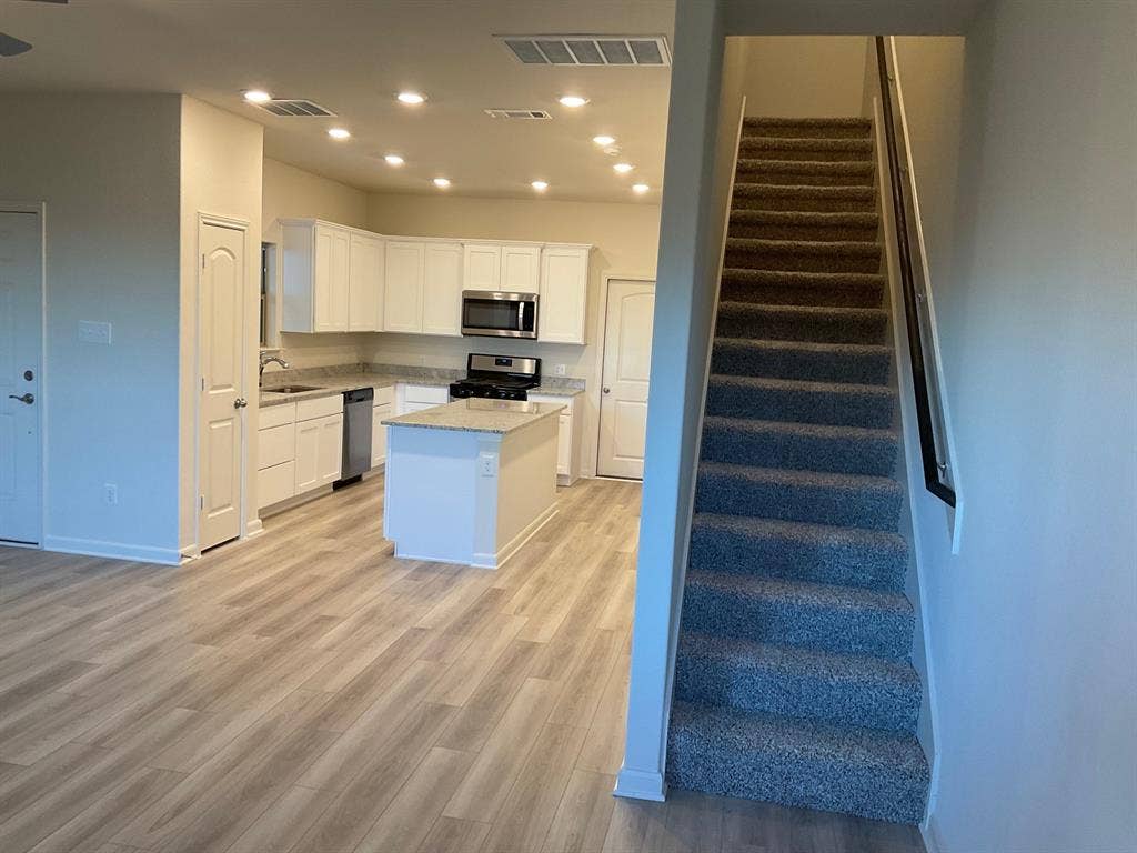 325 Stone Court, Princeton, TX 75407 Kitchen featuring white shaker-style cabinetry, central island, stone-finish countertops, recessed lighting, and wood-finish flooring