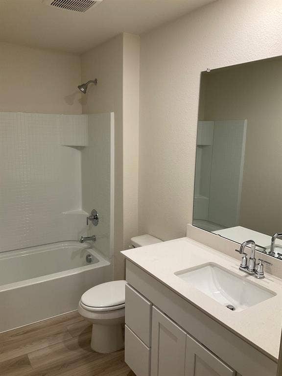 325 Stone Court, Princeton, TX 75407 Bathroom featuring white cabinetry, a solid-surface countertop with an integrated basin, a large wall-mounted mirror, wood-finish flooring, and a tub-shower combination with a tiled surround