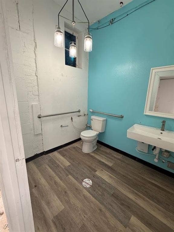 220 N Market Street, Shreveport, LA 71107 Wall-mounted sink with a single-handle faucet, wood-finish flooring, three-light hanging pendant fixture, and stainless steel grab bars
