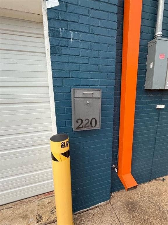 220 N Market Street, Shreveport, LA 71107 Painted brick exterior wall featuring a metal wall-mounted mailbox, high-visibility safety bollard, and integrated gutter system