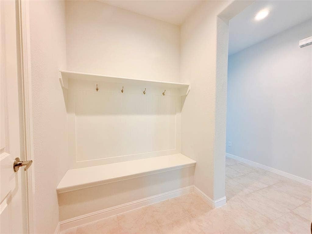 Built-in mudroom bench featuring a custom millwork surround, integrated shelving, and metal hardware hooks