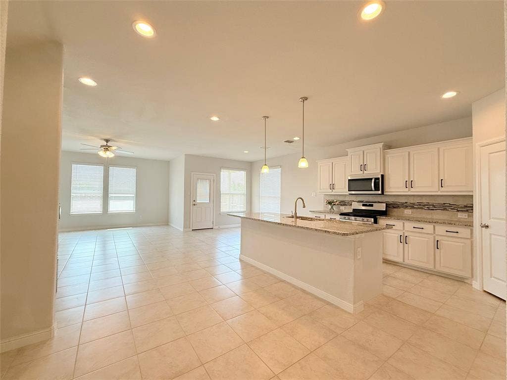 Kitchen featuring an expansive center island, stone-finish countertops, white shaker-style cabinetry, recessed lighting, and tile flooring