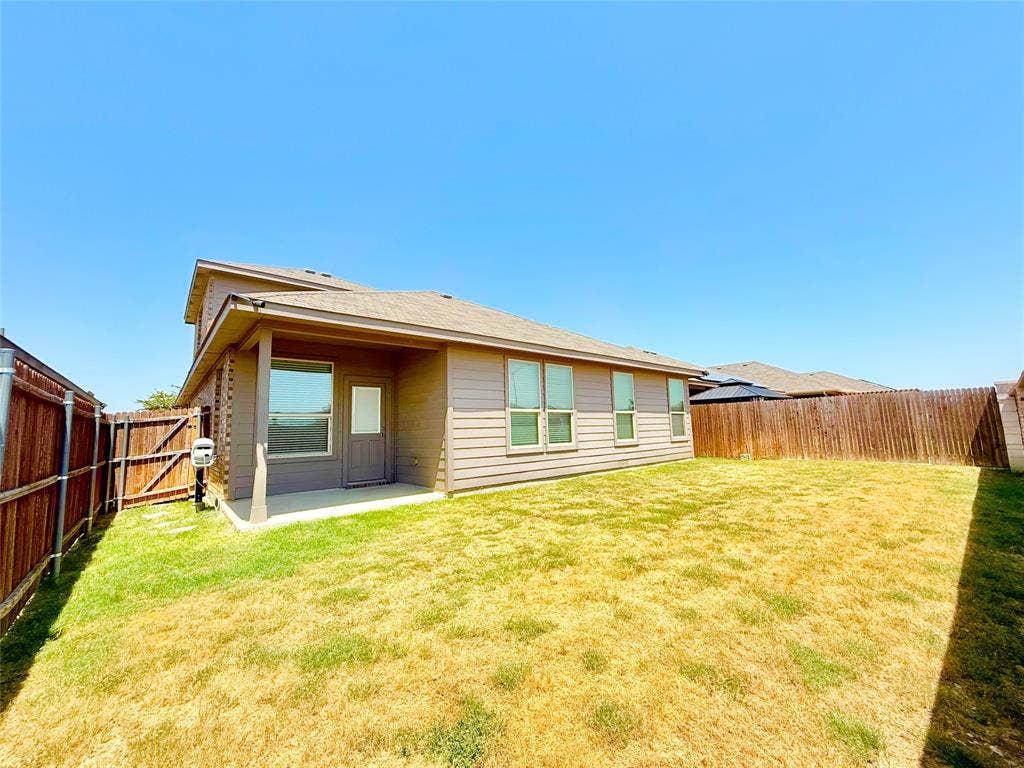 Exterior elevation featuring horizontal siding, a covered patio, and a fully fenced backyard