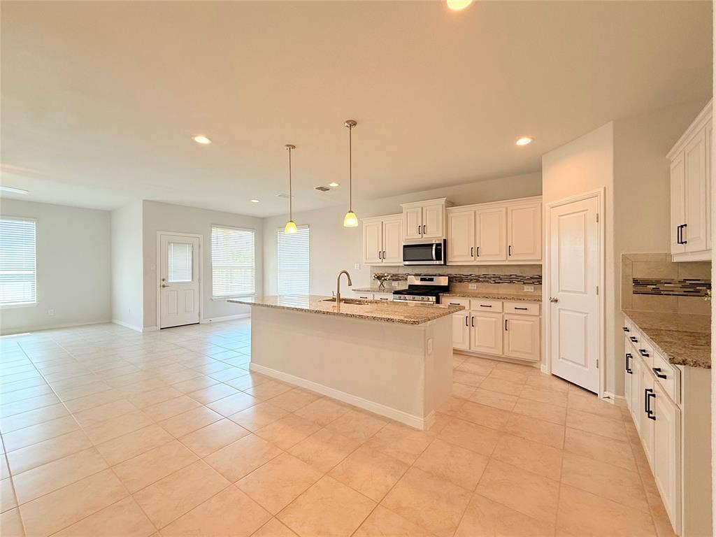 Kitchen featuring a stone-surface island, white cabinetry, decorative tile backsplash, recessed lighting, and pendant fixtures