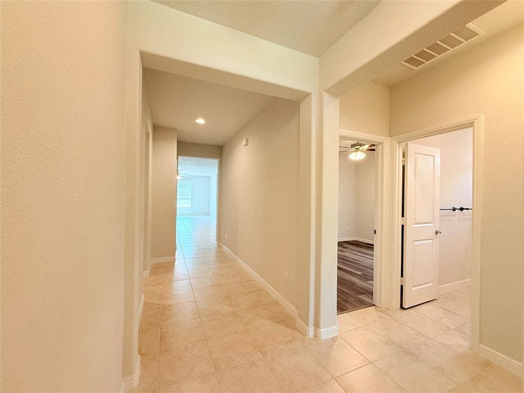 Interior hallway featuring large-format ceramic tile flooring, recessed lighting, and arched architectural entryways
