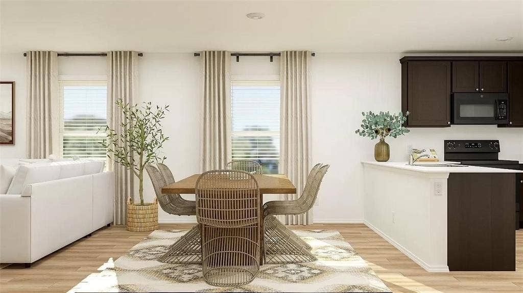 116 Radish Road, Princeton, TX 75407 Open-concept living space featuring wood-finish flooring, recessed lighting, and a kitchen equipped with dark cabinetry, a built-in microwave, and a peninsula with countertop seating