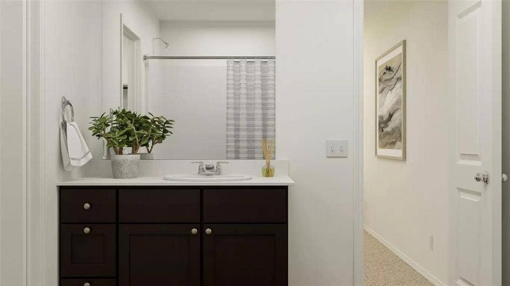 116 Radish Road, Princeton, TX 75407 Dark-finish vanity cabinetry with brushed metal hardware, white solid-surface countertop, integrated basin, and large vanity mirror