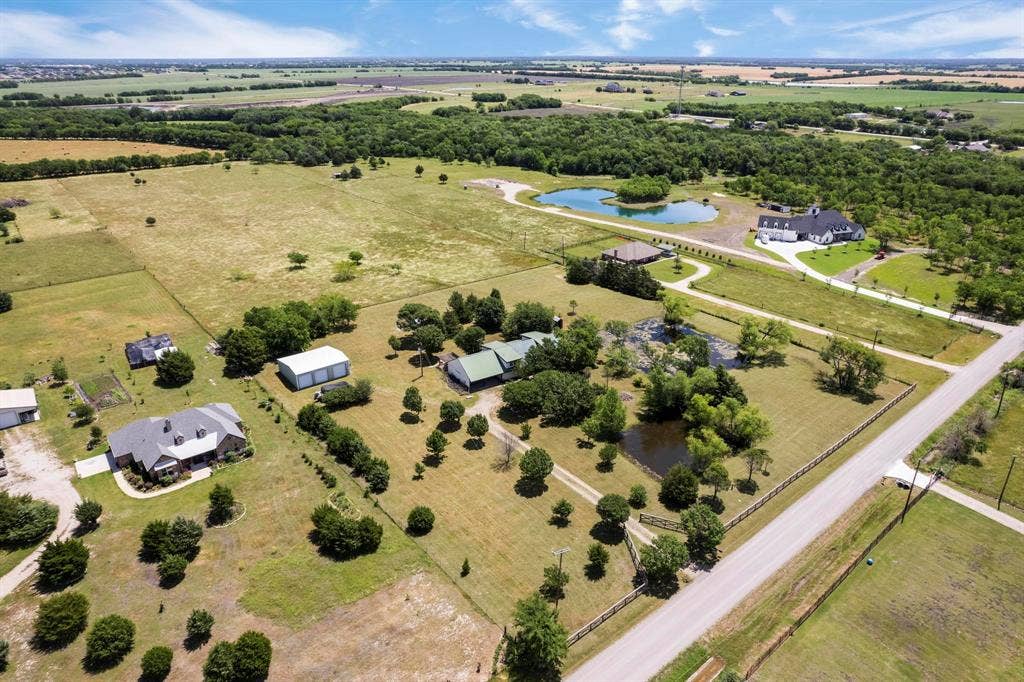 Expansive acreage featuring mature trees, multiple ponds, perimeter fencing, and detached workshop structures