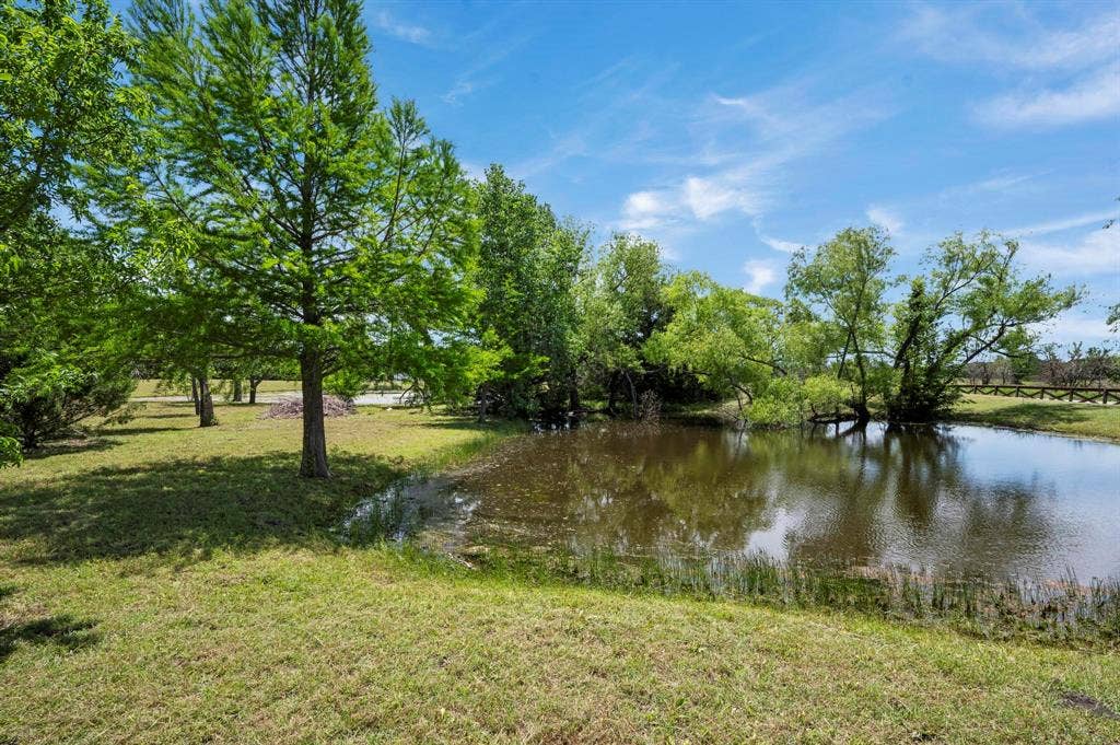 Private pond featuring mature trees and expansive grass acreage