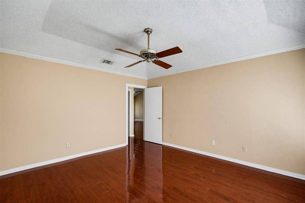 Vaulted ceiling featuring a ceiling fan, polished wood-finish flooring, and crown molding