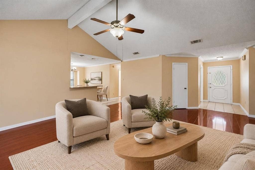Vaulted ceilings, wood-finish flooring, ceiling fan with integrated lighting, pass-through opening, and a paneled entry door with decorative glass inlay