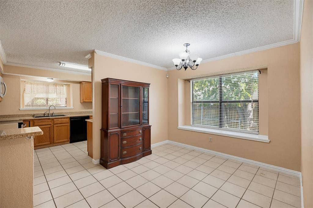 Kitchen featuring tile flooring, stone-surfaced countertops, wood cabinetry, built-in multi-arm light fixture, and large window with built-in sill