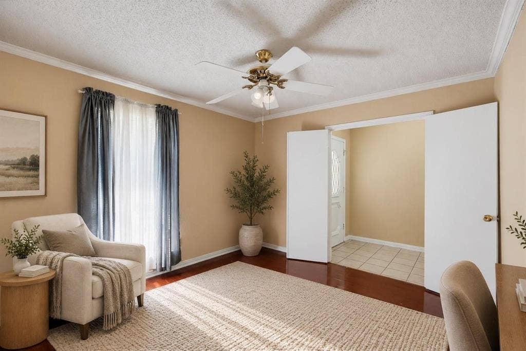 Interior space featuring wood-finish flooring, ceiling fan with integrated lighting, textured ceiling, and crown molding