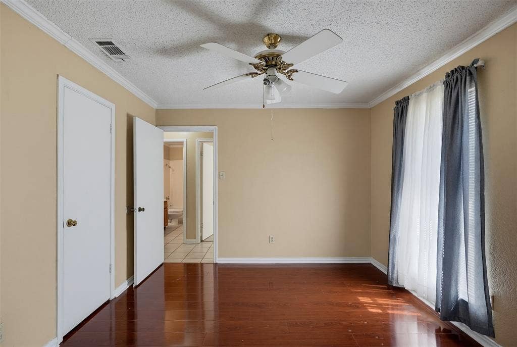 Room featuring wood-finish flooring, crown molding, and a ceiling fan with integrated lighting