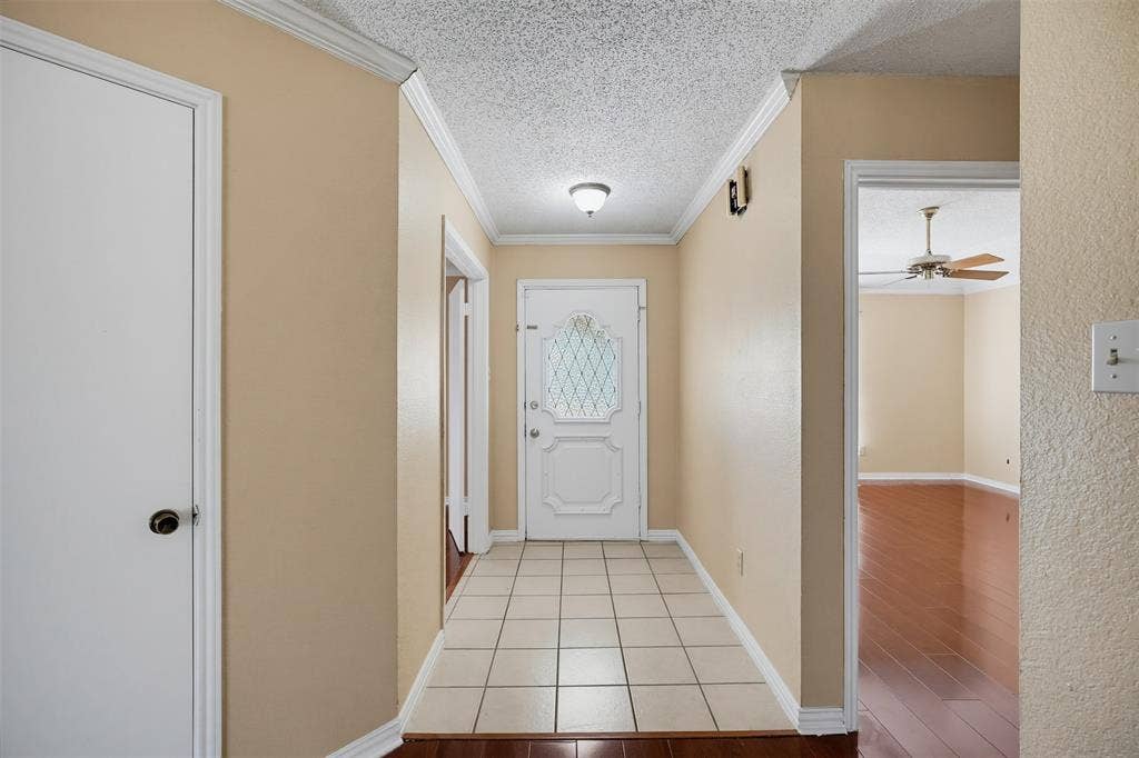 Entryway featuring a white front door with decorative leaded glass, ceramic tile flooring, and crown molding