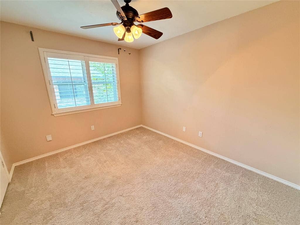 Room featuring neutral wall tones, wall-to-wall carpeting, white plantation shutters, and a central ceiling fan with integrated light fixtures