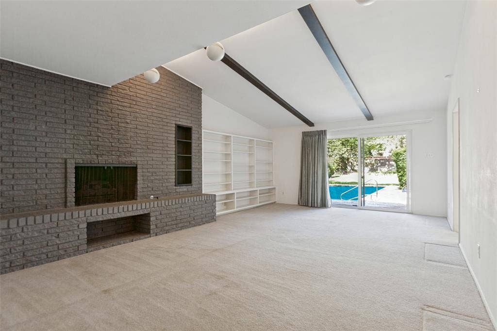 12515 Cedar Bend Drive, Dallas, TX 75244 Sizable living area with striking floor-to-ceiling brick fireplace and built-in shelving.