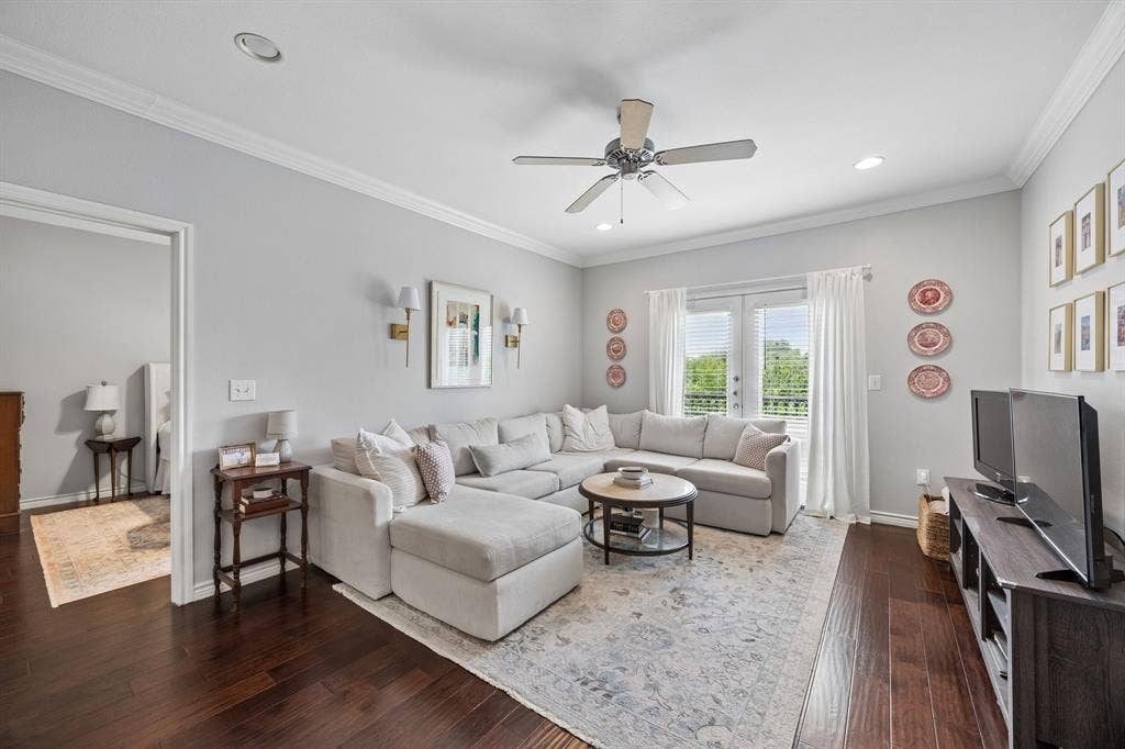 Spacious living area featuring rich wood-finish flooring, crown molding, recessed lighting, and a ceiling fan