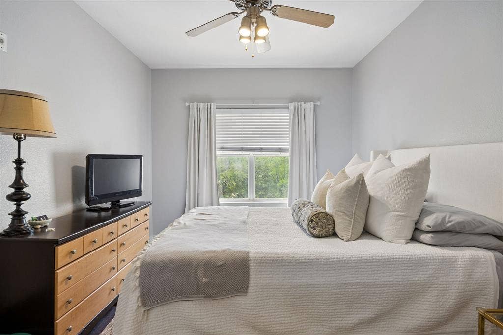 Bright room with a ceiling fan, window with blinds and drapes, and light gray walls