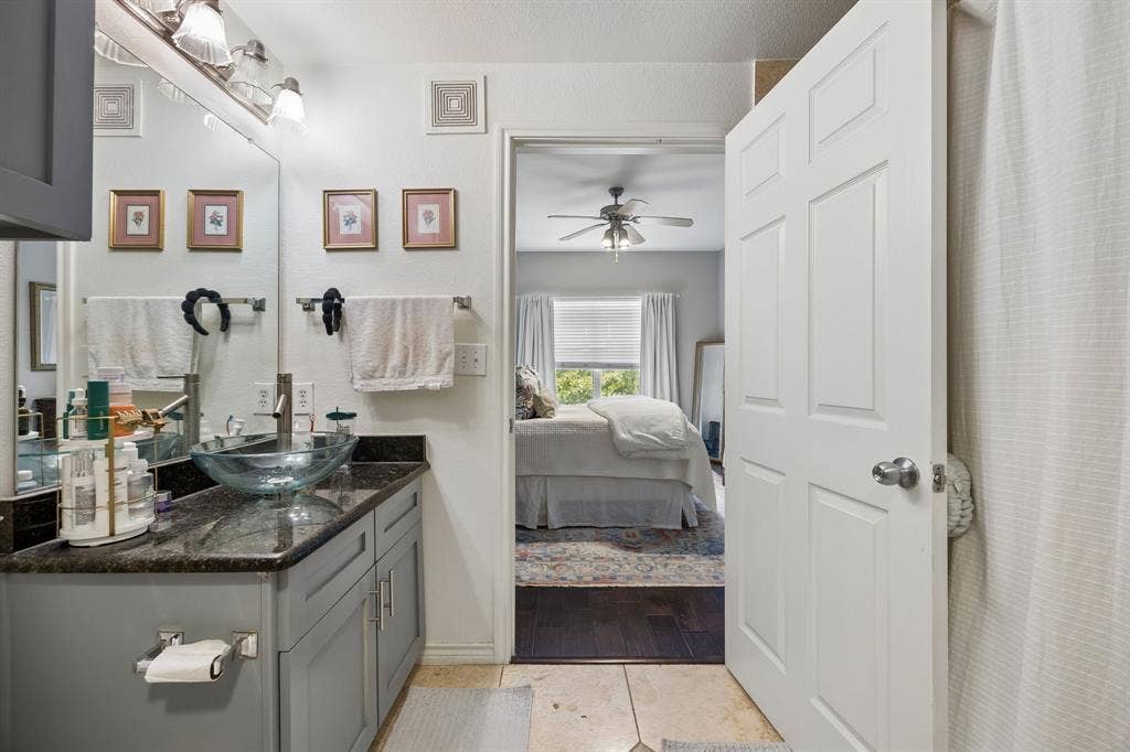 Bathroom featuring a gray vanity with a dark countertop and a glass vessel sink