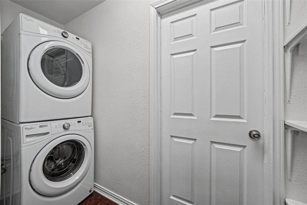 7929 Sunrise Drive, Watauga, TX 76148 Stacked washer and dryer unit, six-panel interior door, and wall-mounted shelving