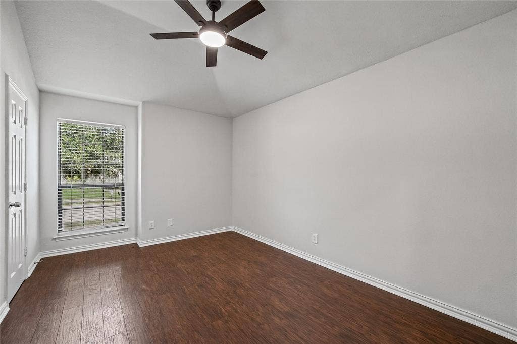 7929 Sunrise Drive, Watauga, TX 76148 Vaulted ceiling featuring a dark-finish ceiling fan with integrated lighting, wood-finish flooring, and a single-pane window