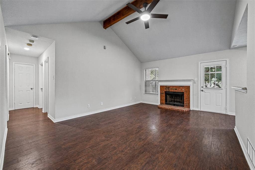 7929 Sunrise Drive, Watauga, TX 76148 Vaulted ceiling featuring a natural wood-finish beam, wood-finish flooring, masonry fireplace with a mantel, and a multi-light exterior door