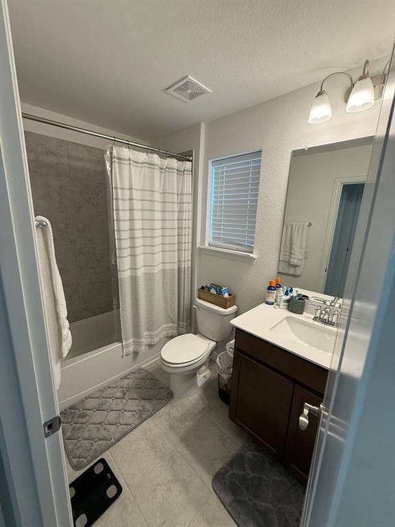 Full bathroom featuring shower / bath combo, vanity, a textured wall, a textured ceiling, and light tile patterned floors