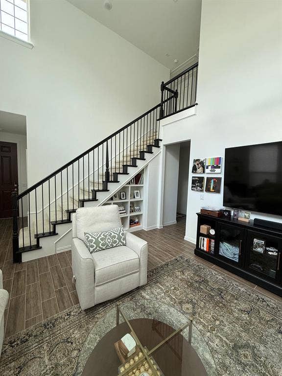 Living area featuring stairway, a towering ceiling, and wood finish floors