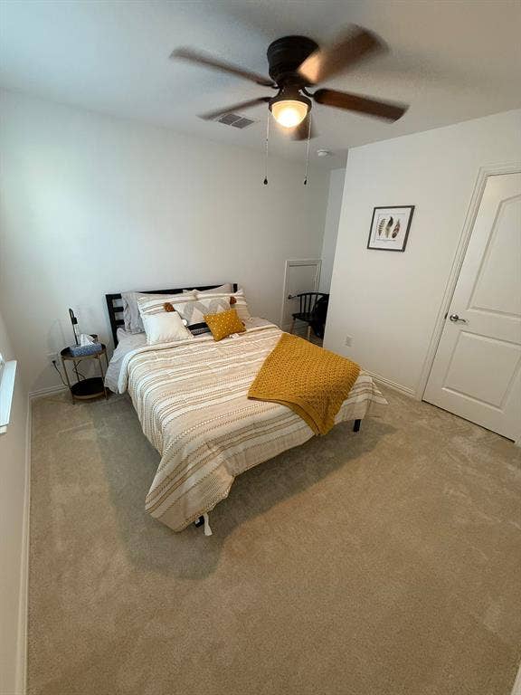 Carpeted bedroom with a ceiling fan and baseboards