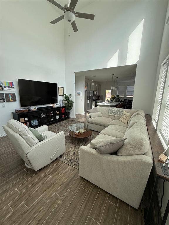 Living room featuring a towering ceiling, wood tiled floors, and a ceiling fan
