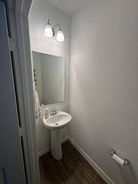 Half bathroom with wood tiled floors and a textured wall