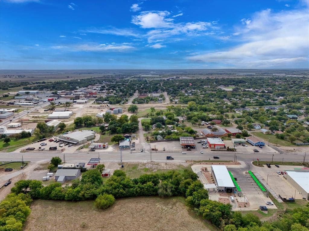 Aerial perspective of expansive open land with mature tree buffers and paved road frontage