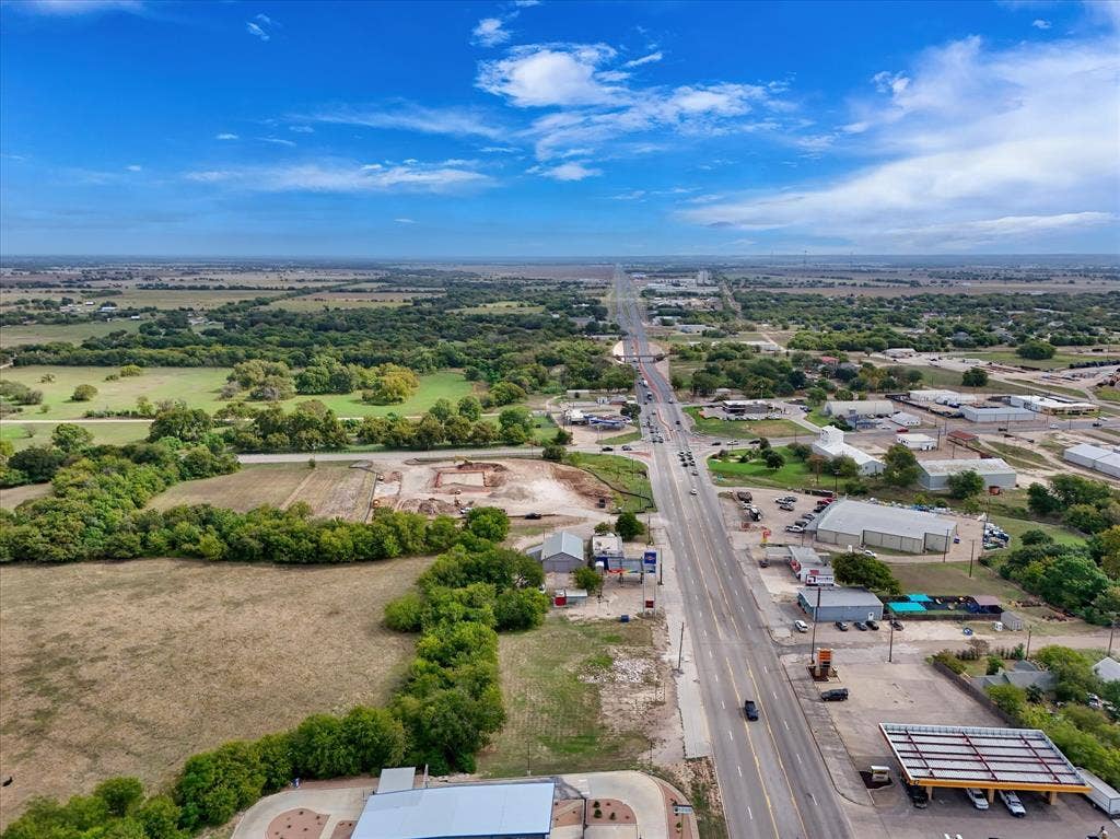 Aerial perspective featuring expansive acreage, mature tree clusters, and direct frontage to a major thoroughfare