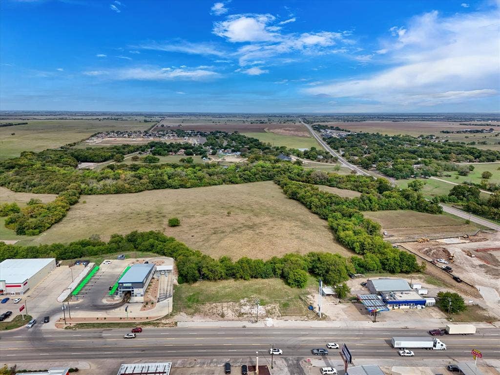 Expansive land tract featuring cleared terrain, mature tree borders, and direct frontage on a major thoroughfare