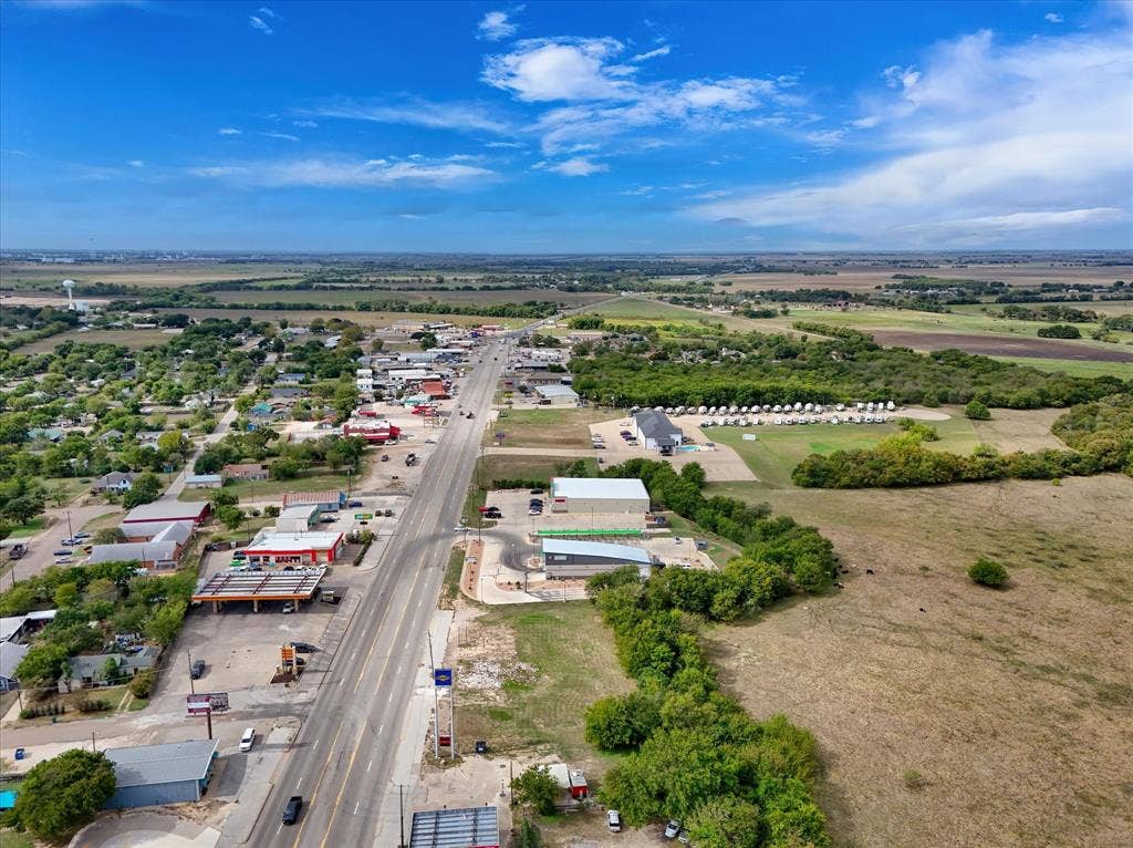Aerial perspective featuring multi-lane road frontage, paved access points, and expansive open acreage