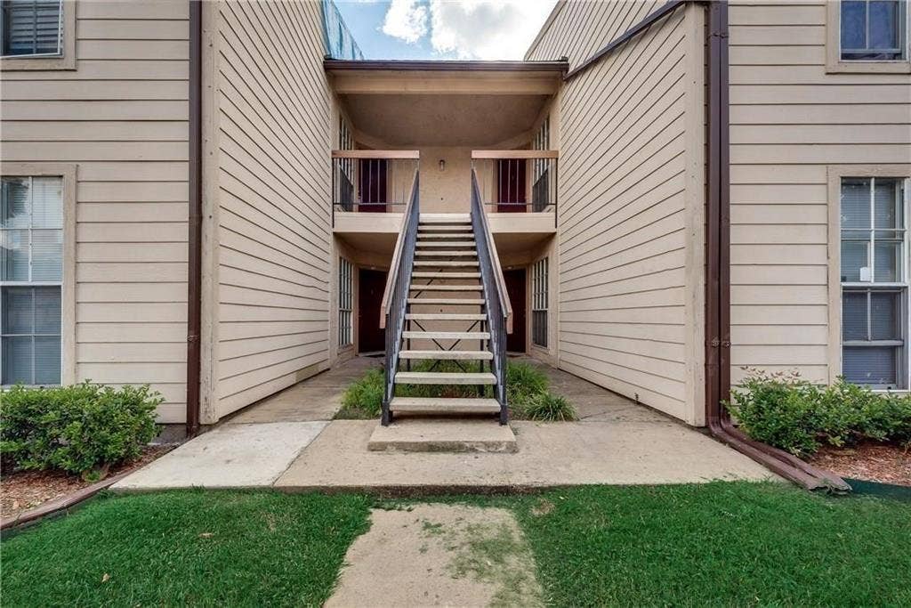 12484 Abrams Road, Dallas, TX 75243 Two-story exterior featuring horizontal lap siding, a central metal staircase with railing, concrete walkway, and multi-pane windows