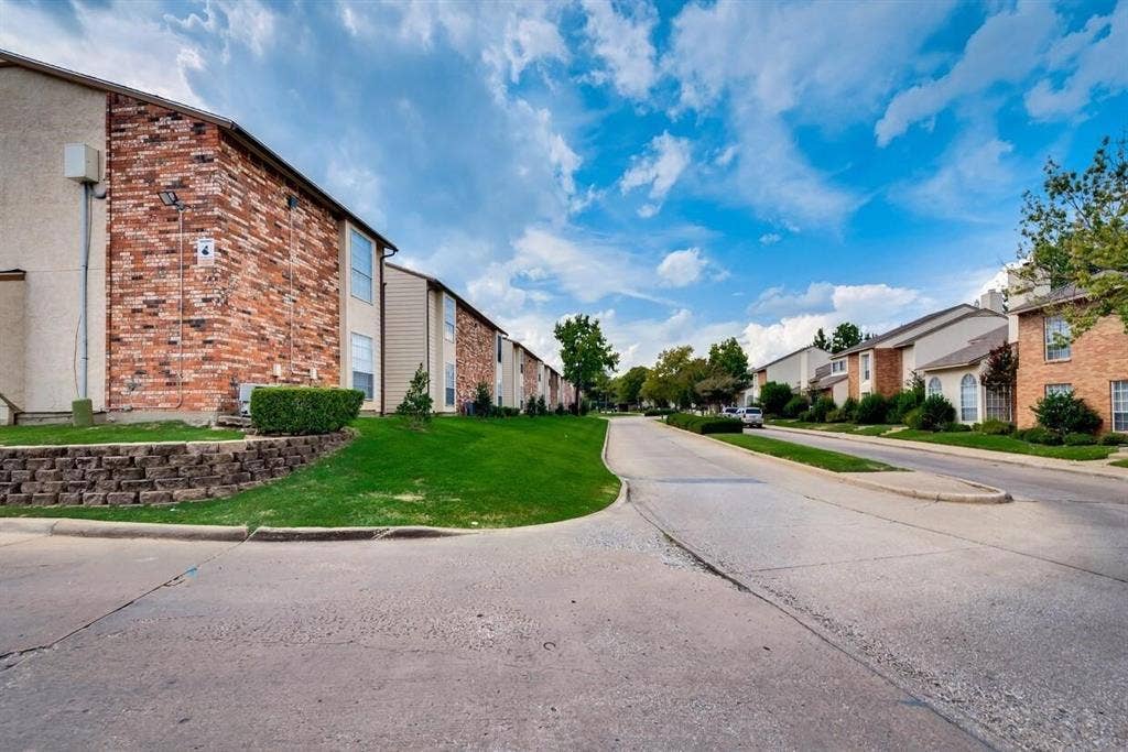 12484 Abrams Road, Dallas, TX 75243 Exterior featuring multi-story brick and siding facades, concrete roadway, retained landscaping, and manicured green space