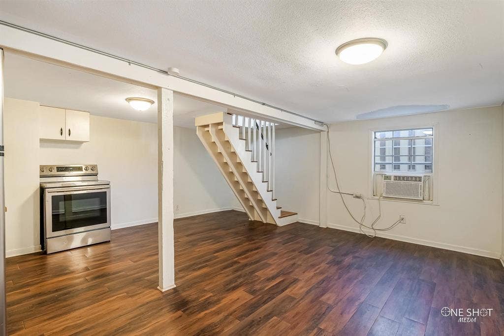 Basement featuring a textured ceiling, cooling unit, and dark hardwood / wood-style floors