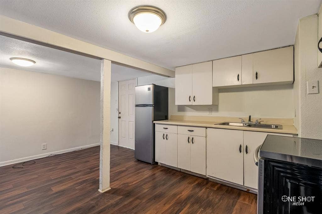 Kitchen with stainless steel fridge, dark hardwood / wood-style flooring, a textured ceiling, and sink