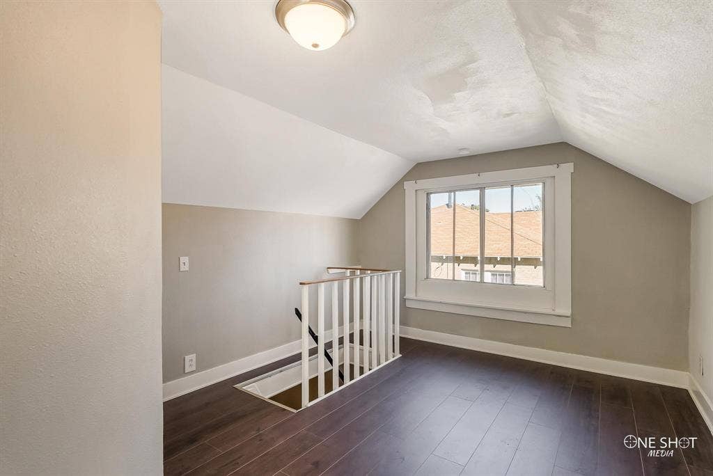 Bonus room featuring a textured ceiling, dark hardwood / wood-style flooring, and vaulted ceiling