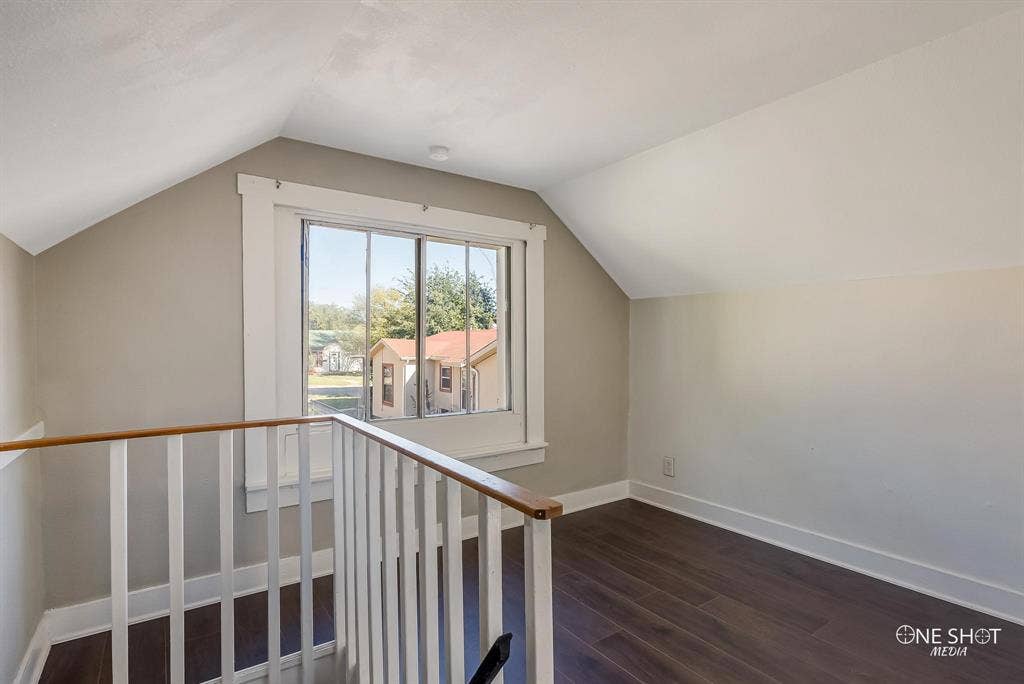 Additional living space with dark hardwood / wood-style flooring and lofted ceiling