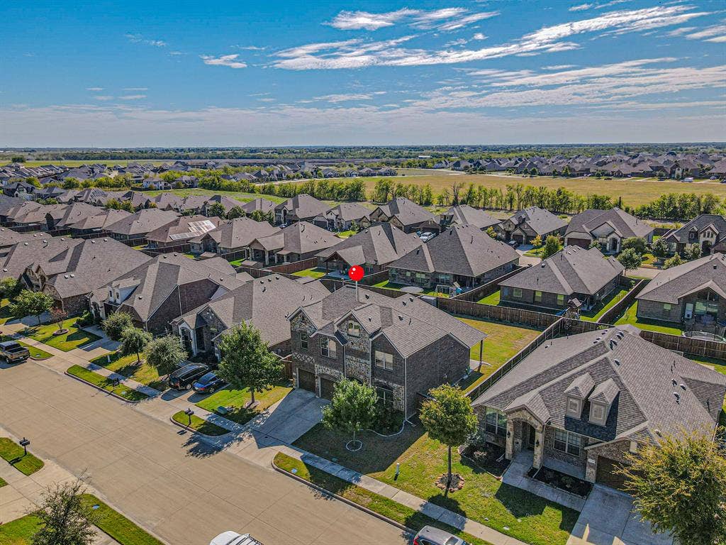 Two-story brick and stone facade, attached multi-car garage, concrete driveway, and landscaped front lawn