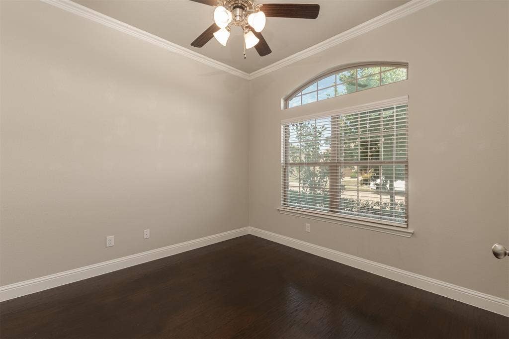 Room featuring high ceilings with crown molding, dark wood-finish flooring, and an arched transom window